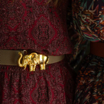 a woman wearing a belt with a gold elephant on it