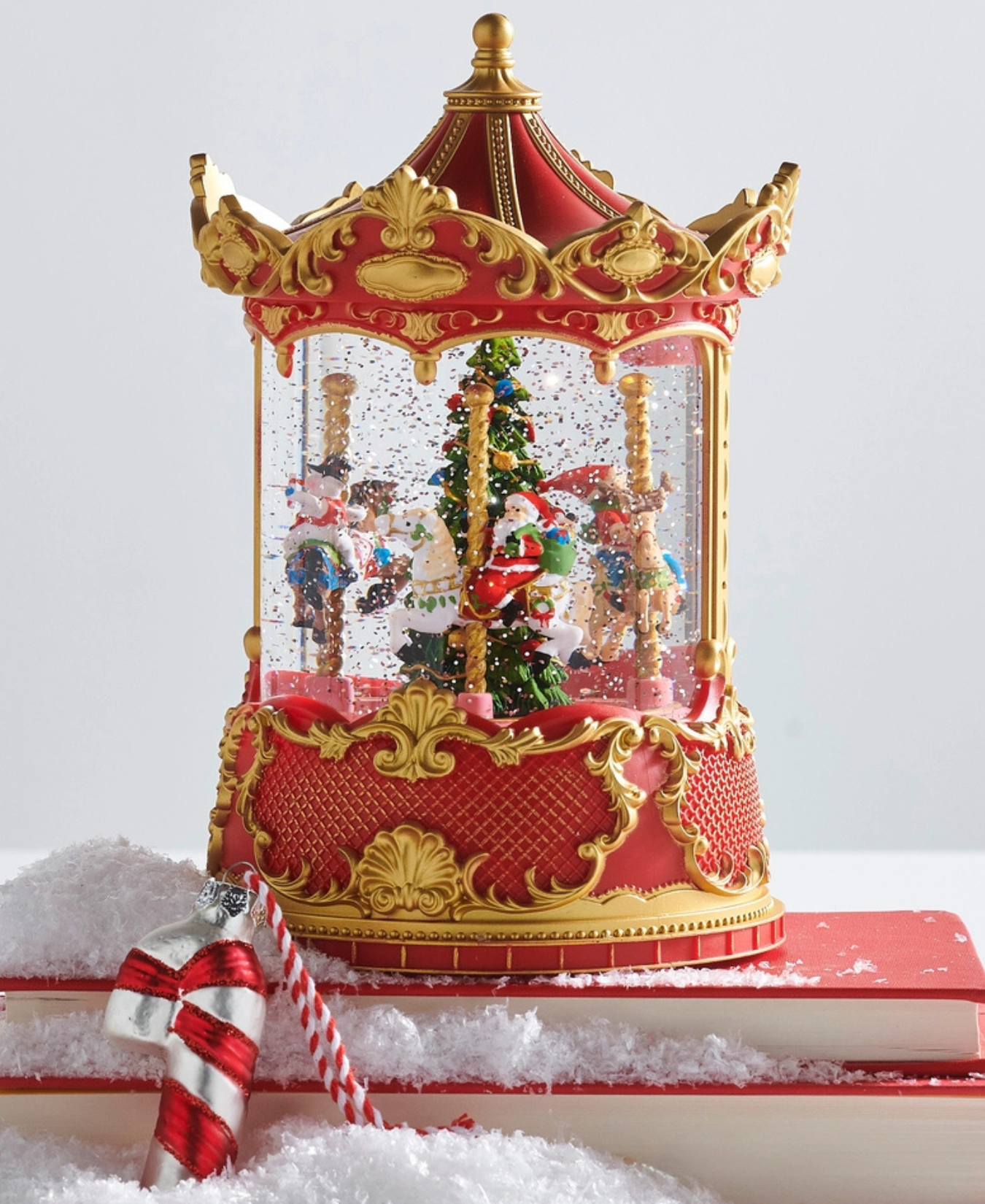 a snow globe with a christmas tree and snow on top of a book