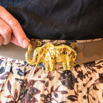 a person wearing a belt with a gold elephant buckle