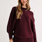 a woman in a maroon sweater and skirt