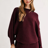 a woman in a maroon sweater and skirt