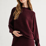 a woman in a maroon sweater and skirt