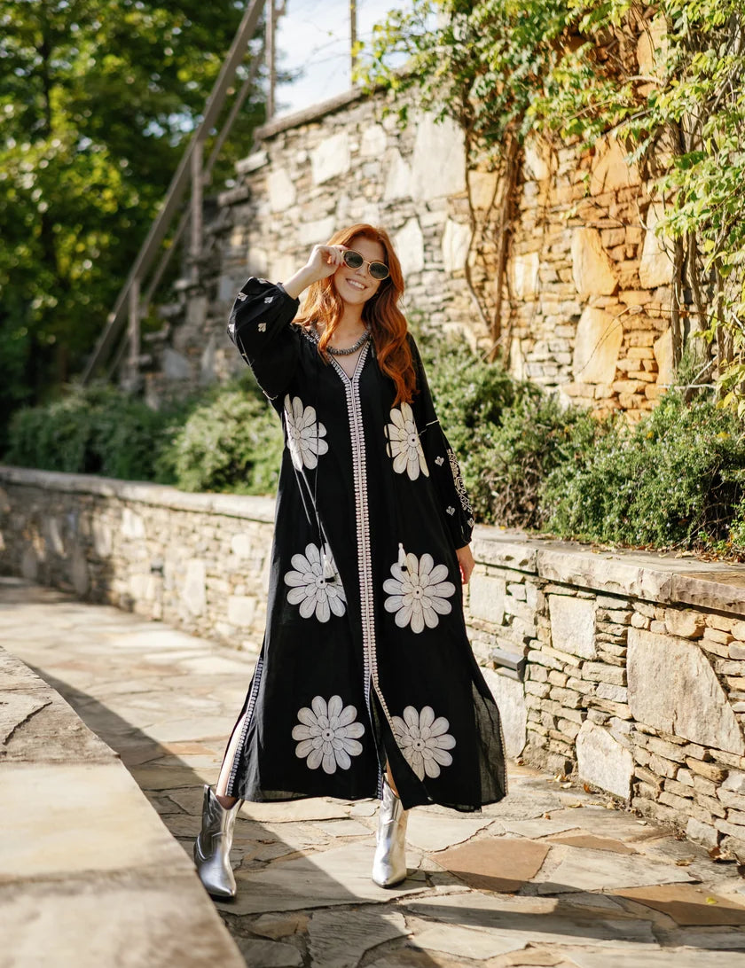 a woman in a long black dress and sunglasses
