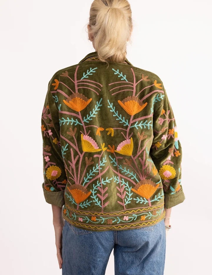 a woman wearing a green jacket with colorful flowers