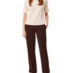 a woman with red hair wearing a white shirt and brown pants