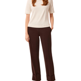 a woman with red hair wearing a white shirt and brown pants