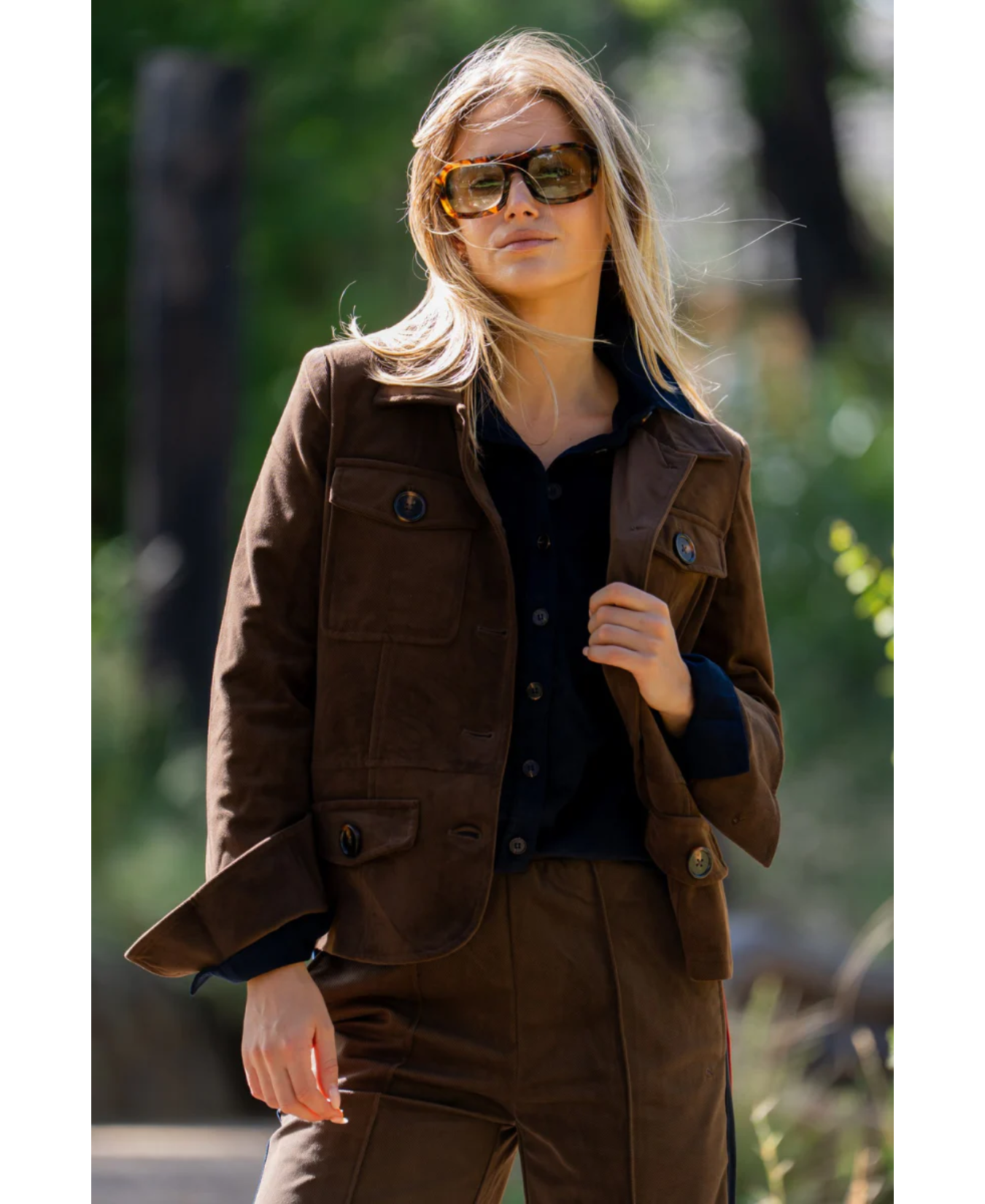 a woman wearing sunglasses and a brown jacket