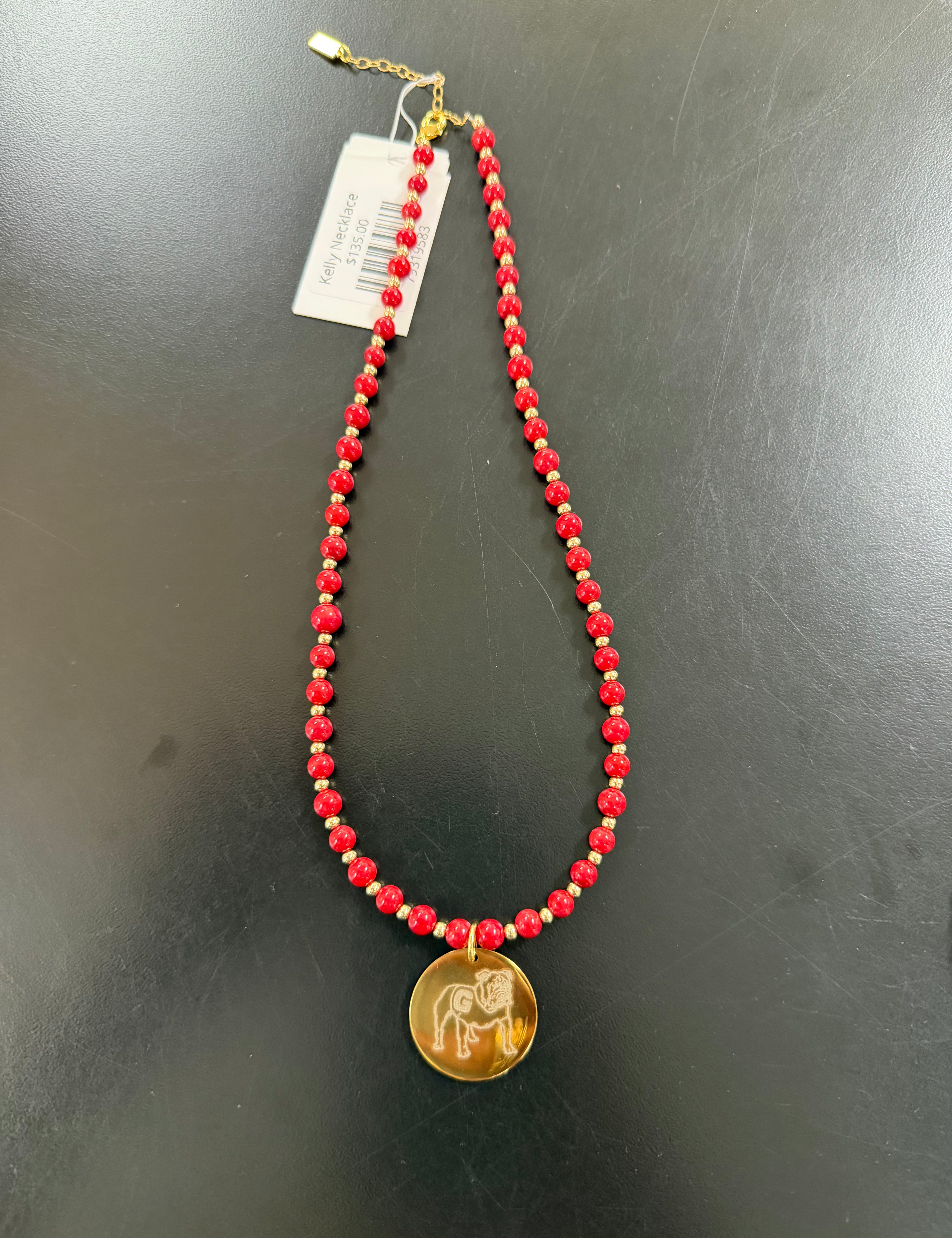 a red beaded necklace with a coin and a tag