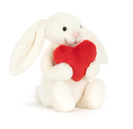 a white stuffed animal rabbit holding a red heart