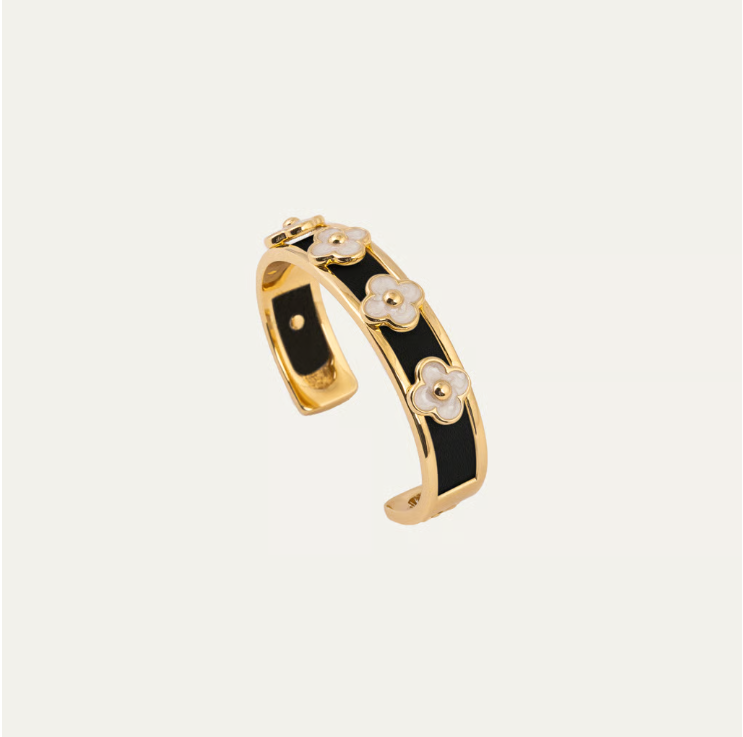 a black and gold bracelet with white flowers
