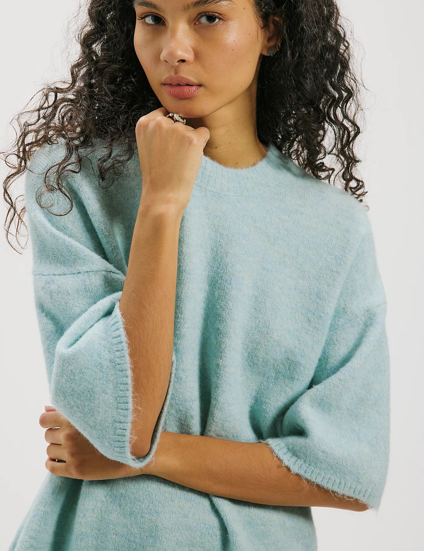 a woman with curly hair wearing a blue sweater