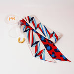 a red white and blue tie with a gold horseshoe and a clear container